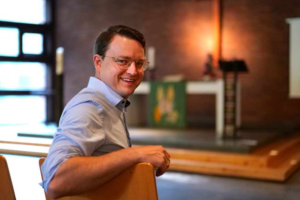 Wolf Tilmann Marek blickt lächelnd über die Schulter in die Kamera. Im Hintergrund ist der Altarraum der Lukaskirche in Gelsenkirchen-Hassel zu erkennen (Foto: Hans-Martin Julius)