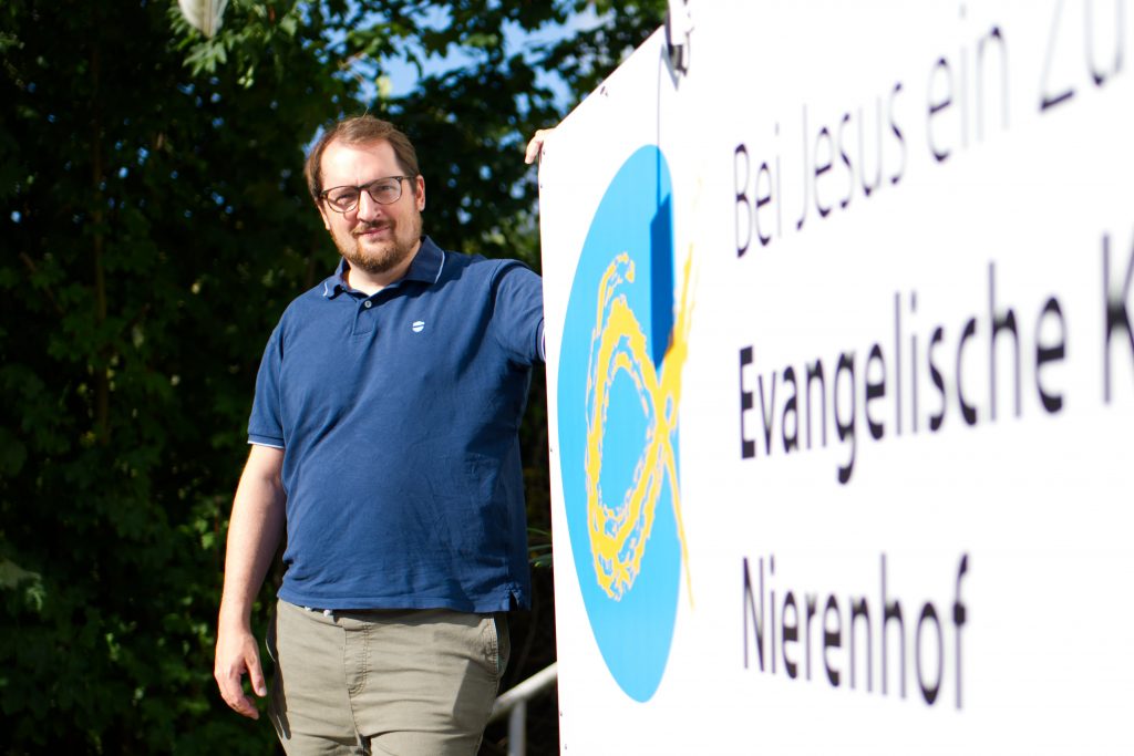 Christian Jünner vor dem Hinweisschild der Evangelischen Kirchengemeinde Nierenhof (Foto: Hans-Martin Julius)