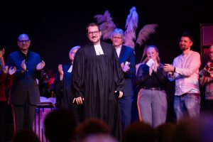 Pfarrer Jünner im Talar im Vordergrund, hinter ihm weitere Teilnehmende des Gottesdienstes (Foto: Ev. Kirchengemeinde Nierenhof)